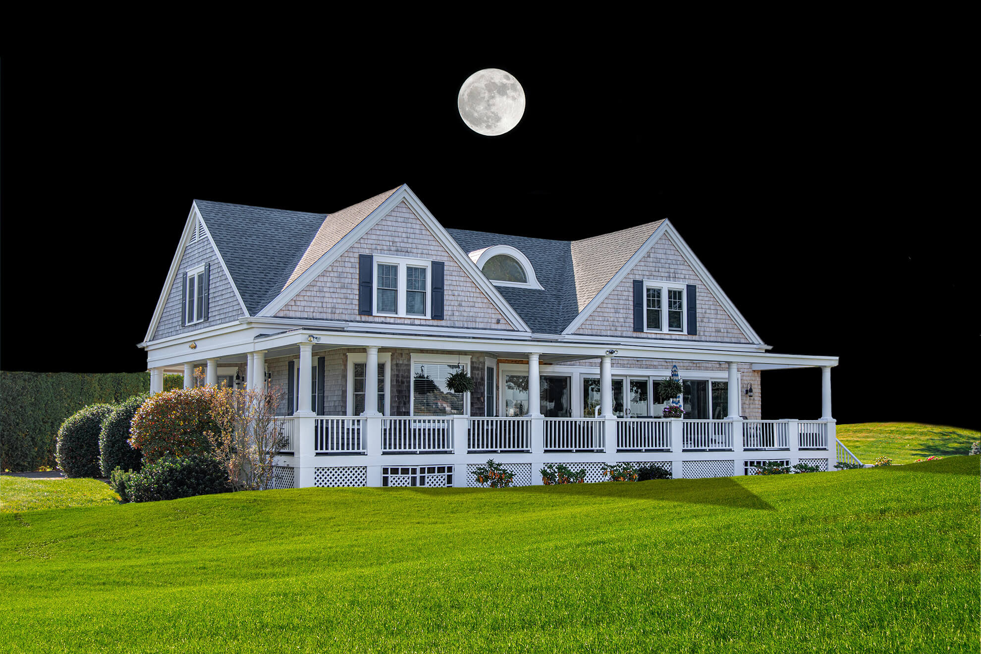 Une maison de style classique avec un grand porche blanc, entourée de pelouses vertes, sous un ciel nocturne avec une pleine lune lumineuse.